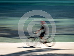 An abstract image of a bicyclist in motion against a blue background. Taken in San Pedro, Ambergris Caye, Belize