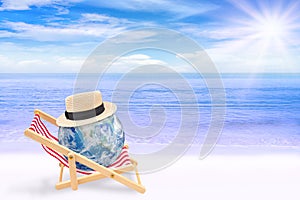 Abstract image of Blue planet earth globe laying relax on beach chair on sand beach with beautiful seascape view in background.