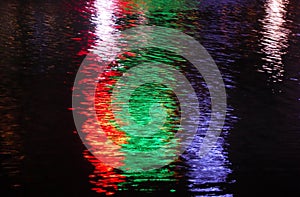 An abstract image of blurred red, blue and green lights reflecting against water