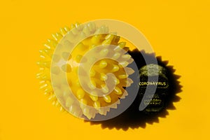 Abstract image of coronavirus. A yellow spiked ball and its shadow with silhouette of a skull and hazard warning text.