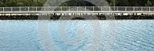 Abstract image of the geometry of borderlines from a canal, a rockfill on the bank, a railing and forest in the background