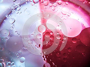 Abstract image of oil and water in a glass bowl sitting on a colorful surface