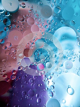 Abstract image of oil and water in a glass bowl sitting on a colorful surface