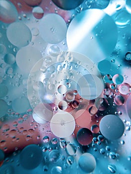 Abstract image of oil and water in a glass bowl sitting on a colorful surface