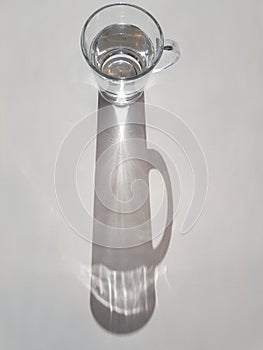 Abstract image of sunlight shining through glass of water, creating a clear ray of light and shadow, hydration theme