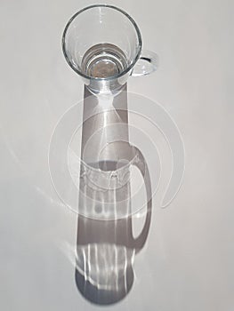 Abstract image of sunlight shining through glass of water, creating a clear ray of light and shadow, hydration theme