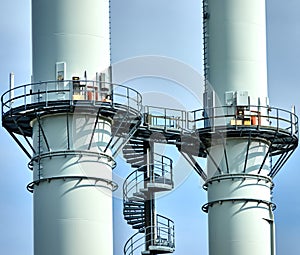 Abstract image of two chimneys with platforms connected by a spiral staircase