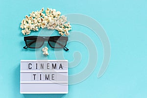 Abstract image of viewer, 3D glasses, popcorn and light box text Cinema time on blue paper background. Concept cinema movie and