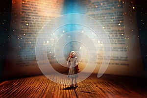 abstract image of woman looking at open book with glowing light . Concept of dream and fantasy