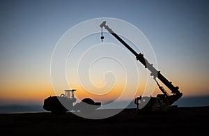 Abstract Industrial background with construction crane silhouette over amazing sunset sky. Mobile crane against the evening sky.
