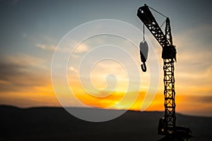 Abstract Industrial background with construction crane silhouette over amazing sunset sky. Tower crane against the evening sky.