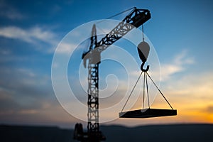 Abstract Industrial background with construction crane silhouette over amazing sunset sky. Tower crane against the evening sky.