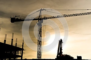 Abstract Industrial background with construction cranes silhouettes over amazing sunset sky