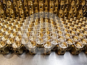 An abstract industrial close-up background of shiny brass metal threaded hexagonal fitting parts