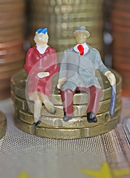 Abstract isolated figures of a retired old couple sitting on a stack of euro coins money - pension and retirement savings concept