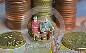 Abstract isolated figures of a retired old couple sitting on a stack of euro coins money - pension and retirement savings concept