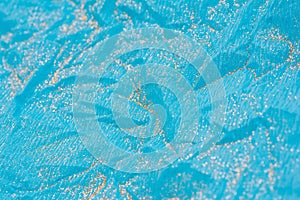 Abstract macro blue crumpled paper background with gold glitter