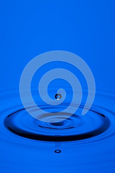 Abstract Macro Shot of The Only Blue Water Droplet Over Tranquil Water Surface