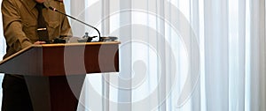 Abstract man in a green shirt stands on the podium in front of a microphone. Close-up. Copy space. Concept speech of a military