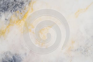 Abstract marble texture with white, gray, and yellow swirls and veins
