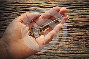 Abstract of metal key on left hand against textured of bark wood