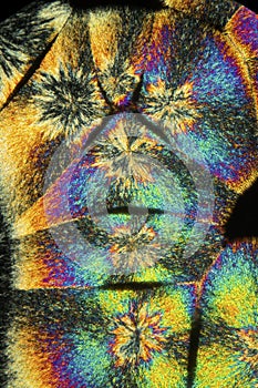 Abstract micrograph of colorful rounded stacks of lysine crystal