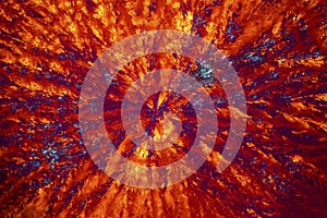 Abstract micrograph of orange and blue lysine crystals.