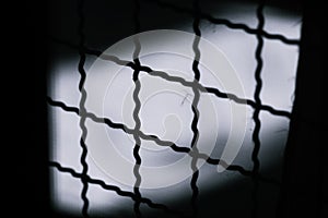 Abstract Minimal style black and whith rays of sunlight cast shadows on the wire mesh steel metal