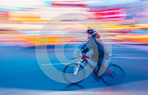 Abstract motion blurry image of unrecognizable cyclist on the night city roadway. Intentional motion blur