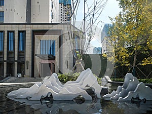 Abstract Mountain Sculptures in Reflective Pool Before Contemporary Building