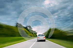 Abstract Natural Blurred Background Of Luxury Suv Car In Fast Motion On Road At Summer. Cloudy Sky Above Asphalt