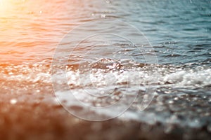 Abstract nature summer ocean sunset sea background. Small waves on water surface in motion blur with bokeh lights from
