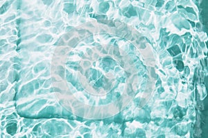 Abstract nature textured background, waves with sun reflection. Clear water with bubbles and circles on blue background