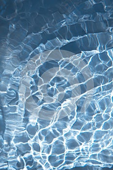 Abstract nature textured background, waves with sun reflection. Clear water with bubbles and circles on blue background