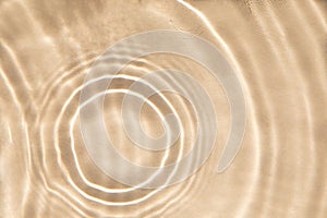 Abstract nature textured beige background, water waves with sun reflection. Clear water with bubbles and circles