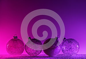 Abstract neon purple and pink gradient glitter glass Christmas baubles background with copy space.