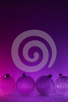 Abstract neon purple and pink gradient glitter glass Christmas baubles background with copy space.