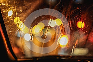 Abstract night city light and bokeh through car windscreen covered in rain, background