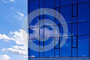 Abstract office building background. Clouds and sky reflected in windows of modern office building. Skyscraper in the city