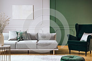 Abstract oil painting on grey wall with moldings in contemporary living room interior with grey long couch