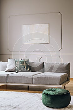 Abstract painting on grey wall with moldings in contemporary living room interior with grey long couch