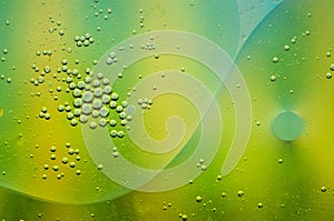 Abstract of olive oil floating on water with green, turquoise an