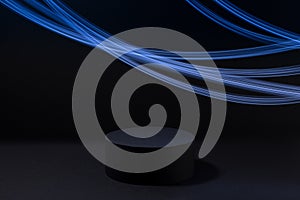 Abstract one black round podium for cosmetic products with glowing neon blue light stripes in motion, mockup