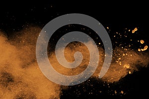 Abstract orange dust explosion on black background.