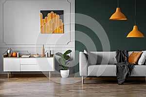 Abstract orange painting on grey wall of stylish living room interior with white wooden furniture and grey couch photo