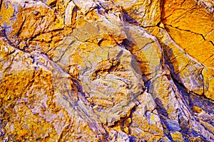 Abstract orange yellow blue background. Colorful rock texture. Cracked layered mountain surface.