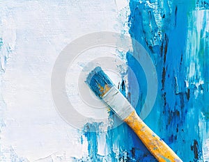 Abstract painting canvas in white oil paint with blue painted half and paintbrush