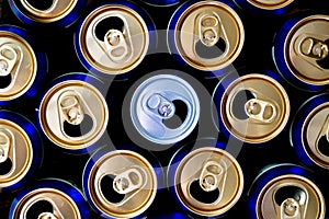Abstract pattern of opened aluminium cans, top view. One white soda or beer can standing out among yellow and blue cans.