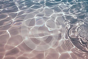 Abstract pattern of sunlight reflecting on clear blue and pink water surface