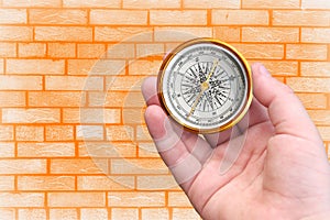 Abstract photo with compass in hand on brick wall background